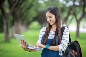 beautiful Asian girl student holding books and smiling at camera and learning and education concept  on park in summer for relax time photo