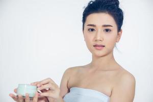 A beautiful woman asian using a skin care product, moisturizer or lotion taking care of her dry complexion. Moisturizing cream in female hands . photo