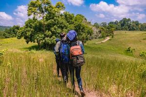 Asian Group of young people Hiking with friends backpacks walking together and looking map and taking photo camera by the road and looking happy ,Relax time on holiday concept travel