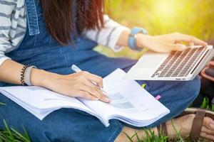 beautiful Asian girl student holding books and smiling at camera and learning and education concept  on park in summer for relax time photo