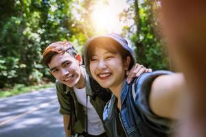 grupo asiático de jóvenes con amigos y mochilas caminando juntos y amigos felices tomando fotos y selfies, tiempo de relajación en viajes de concepto de vacaciones