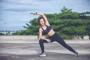 mujer atlética asiática calentándose y joven atleta sentada en un ejercicio y estirándose en un parque antes de correr al aire libre, concepto de estilo de vida saludable foto