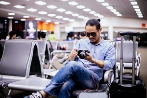 hombre asiático con mochila viajero revisando la imagen en la cámara en un aeropuerto