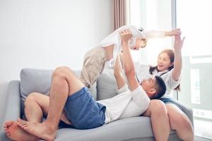 Happy Asian family with son at home on the sofa playing and laughing photo