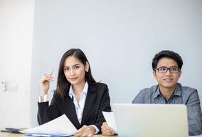 Hombres de negocios asiáticos y grupo que usan el cuaderno para socios comerciales que discuten documentos e ideas en reuniones y mujeres de negocios sonriendo felices por trabajar foto