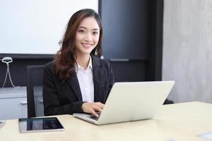 Mujeres de negocios asiáticas que usan el cuaderno y sonríen felices por trabajar
