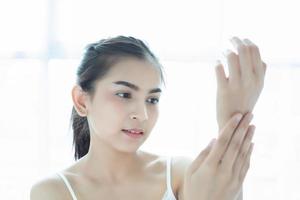 A beautiful woman asian using a skin care product, moisturizer or lotion taking care of her dry complexion. Moisturizing cream in female hands . photo