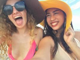 las mujeres están tomando fotos y selfie con amigos en la playa de arena en el verano.