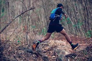 A man Runner of Trail . and athlete's feet wearing sports shoes for trail running in the forest photo