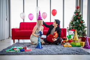 pareja asiática amante está dando una caja de regalo con regalo de navidad en vacaciones de navidad y feliz patty de año nuevo foto