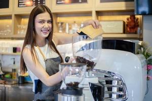 Las mujeres asiáticas barista sonriendo y usando la máquina de café en el mostrador de la cafetería - mujer trabajadora propietario de una pequeña empresa comida y bebida concepto de cafetería foto