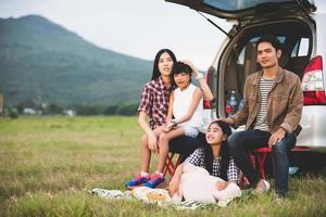 Niña feliz con familia asiática sentada en el coche para disfrutar de un viaje por carretera y las vacaciones de verano en autocaravana foto