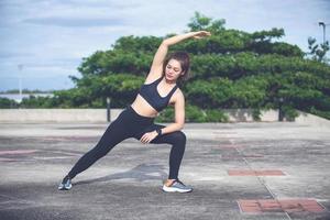 mujer atlética asiática calentándose y joven atleta sentada en un ejercicio y estirándose en un parque antes de correr al aire libre, concepto de estilo de vida saludable foto