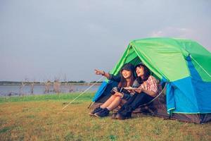 A group of Asian friends tourist drinking together with happiness in Summer while having camping photo