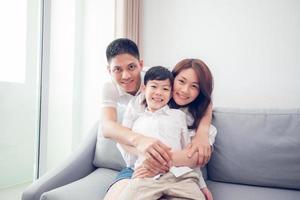 Happy Asian family with son at home on the sofa playing and laughing photo