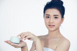 A beautiful woman asian using a skin care product, moisturizer or lotion taking care of her dry complexion. Moisturizing cream in female hands . photo