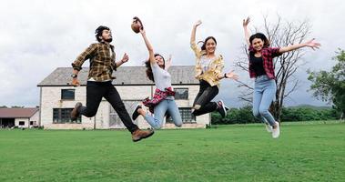 Successful Young students at campus looking at camera and smiling and high five while jumping on outdoors.