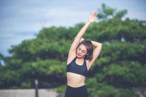 mujer atlética asiática calentándose y joven atleta sentada en un ejercicio y estirándose en un parque antes de correr al aire libre, concepto de estilo de vida saludable foto