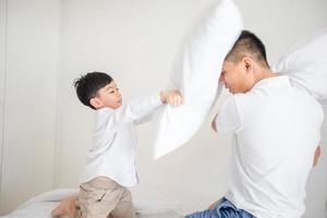 Feliz familia asiática con su hijo en casa en el dormitorio jugando y riendo foto