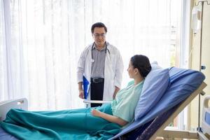 The doctors are asking and explaining about the illness to a female patient lying in bed at a hospital. photo