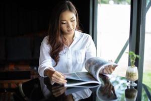 Las mujeres asiáticas sonriendo y leyendo un libro para relajarse en la cafetería. foto