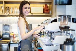 Las mujeres asiáticas barista sonriendo y usando la máquina de café en el mostrador de la cafetería - mujer trabajadora propietario de una pequeña empresa comida y bebida concepto de cafetería foto