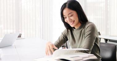 Asian women Students Smile and reading book and using notebook for helps to share ideas in the work and project. And also review the book before the exam photo