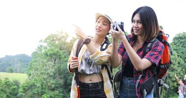 Asian Group of young people Hiking with friends backpacks walking together and looking map and taking photo camera by the road and looking happy ,Relax time on holiday concept travel