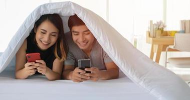 Asian couple lovers lying on their play mobile phones on bed photo
