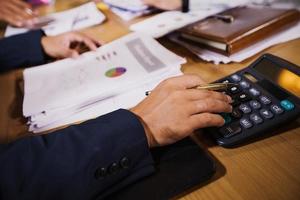 Businessmen are using calculators and analysis business data and and graph financial diagram working  at the meeting. photo