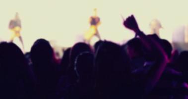silhouettes of concert crowd at Rear view of festival crowd raising their hands on bright stage lights photo