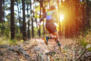 A man Runner of Trail and athlete's feet wearing sports shoes for trail running in the forest photo