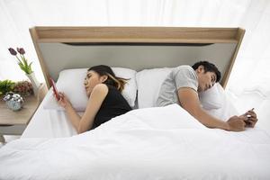 Asian couple lovers lying on their play mobile phones on bed photo