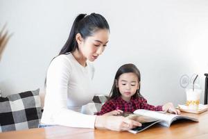 Mom is teaching her daughter to read a book. photo