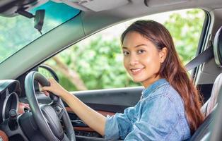 Hermosa mujer asiática sonriendo y disfrutando de conducir un coche en la carretera para viajar foto