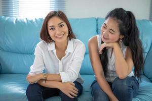 retrato de estilo de vida mujeres asiáticas de mejores amigos - sonriendo feliz en el sofá en la sala de estar