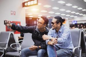 Asian man with backpack  traveler using the smart mobile phone for Video call and taking photo at an airport,Blurry and soft focus