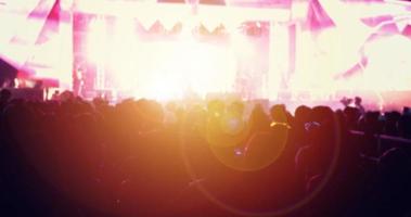 Siluetas de multitud de conciertos en la vista trasera de la multitud del festival levantando sus manos sobre las luces del escenario brillante foto