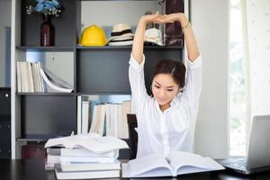 Asian woman stretching after reading book and work hard and smiling in the home office photo