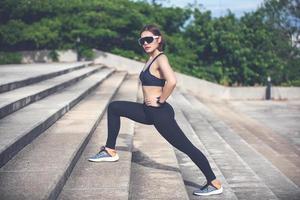 mujer atlética asiática calentándose y joven atleta sentada en un ejercicio y estirándose en un parque antes de correr al aire libre, concepto de estilo de vida saludable foto