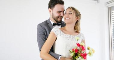 los amantes le dan flores a la novia y se besan felices y la pareja ama de pie en el estudio de bodas foto
