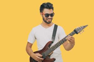 Handsome young asian men playing guitar and  listen music with headphones  isolated on yellow background photo