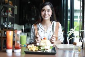 Mujeres asiáticas sonrientes y felices y disfrutaron comiendo hamburguesas en el café y el restaurante en el momento de relajarse foto