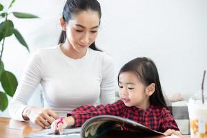 Mom is teaching her daughter to read a book. photo