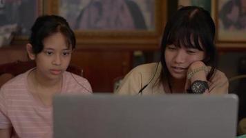 Two teen schoolgirls studying lesson online on laptop at home. video