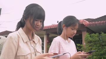 Two girls texting on social media online with mobile phone while walking together. video