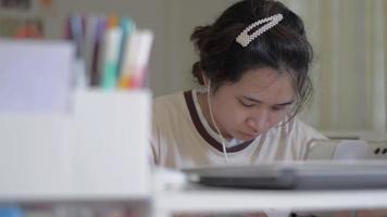 weibliche universitätsstudentin, die zu hause online auf einem digitalen gerät lernt.