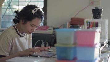 estudante universitário feminino mensagem de texto on-line para amigos no dispositivo digital em casa. video