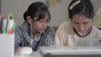 Two sisters working together with digital tablet on the desk at home. video