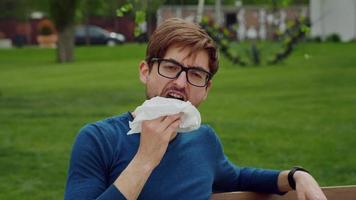 Handsome man enjoying food in park. video